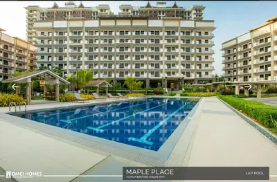 a swimming pool in front of a large building at Staycacia Haven 2BR Condo Maple Acacia Taguig in Manila