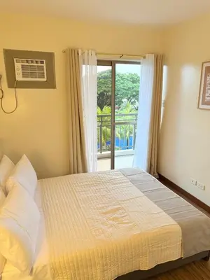 a bedroom with a bed and a window with a balcony at Staycacia Haven 2BR Condo Maple Acacia Taguig in Manila