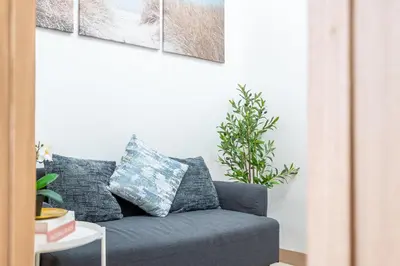 a gray couch in a living room with paintings on the wall at Stylish Makati 1BR w Balcony Netflix and Fast Wifi in Manila