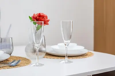 a table with two wine glasses and a vase with a rose at Stylish Makati 1BR w Balcony Netflix and Fast Wifi in Manila