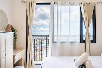 a bedroom with a bed and a large window at Stylish Makati 1BR w Balcony Netflix and Fast Wifi in Manila