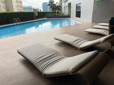 a pool with three chaise lounging chairs next to a pool at Stylish Makati 1BR w Balcony Netflix and Fast Wifi in Manila