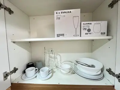a shelf with plates and cups and a box on it at Stylish Makati 1BR w Balcony Netflix and Fast Wifi in Manila