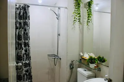 a bathroom with a shower curtain and a toilet at Casa Neutra - A Cozy Retreat in Manila in Manila