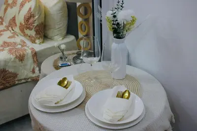 a white table with plates and gold napkins on it at Casa Neutra - A Cozy Retreat in Manila in Manila