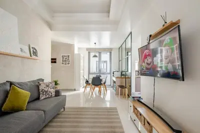 a living room with a couch and a tv on a wall at Greenbelt Hamilton Residences by ChiKat in Manila