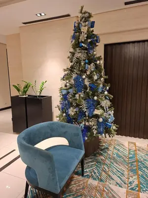 a christmas tree and a blue chair in a room at Greenbelt Hamilton Residences by ChiKat in Manila