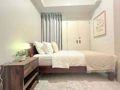 a bedroom with a bed and a dresser with a lamp at Greenbelt Hamilton Residences by ChiKat in Manila