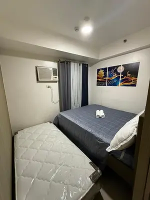 a small bedroom with two beds and a air conditioner at City view in Manila