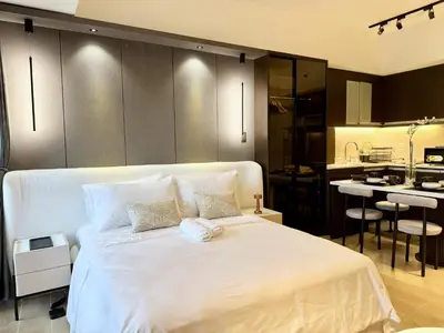 a bedroom with a large white bed and a kitchen at Venice Canal View with Balcony near BGC and Airport 10c in Manila