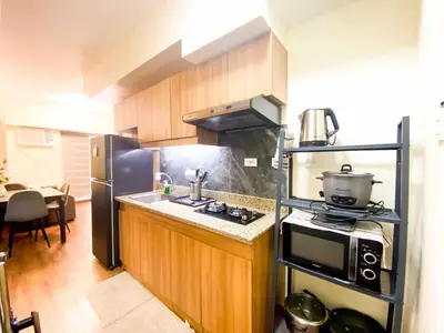 a kitchen with a stove and a microwave at Prisma Residences - 1 Bedroom Paid Parking & Kitchen Near BGC in Manila