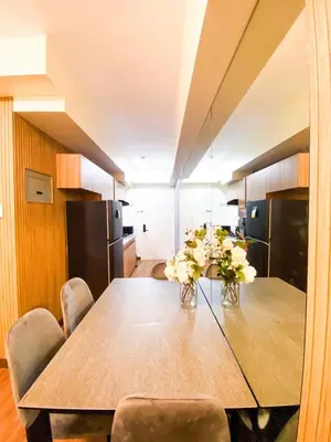 a dining room with a table with flowers on it at Prisma Residences - 1 Bedroom Paid Parking & Kitchen Near BGC in Manila