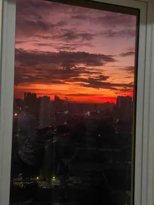 a sunset view of a city from a window at Prisma Residences - 1 Bedroom Paid Parking & Kitchen Near BGC in Manila