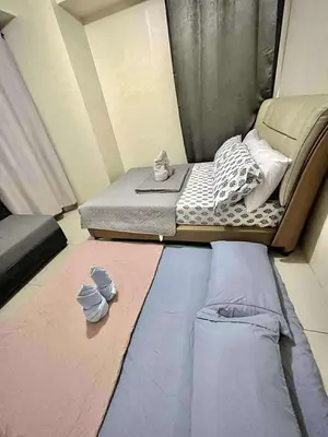 a small bed in a small room with clothes on the floor at Staycation Near Mall of Asia in Manila
