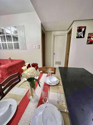 a table with plates and a vase of flowers on it at Staycation Near Mall of Asia in Manila