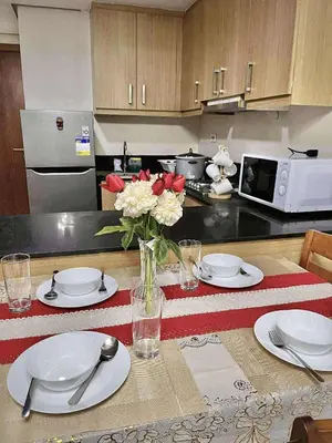 a kitchen with a table with plates and a vase of flowers at Staycation Near Mall of Asia in Manila