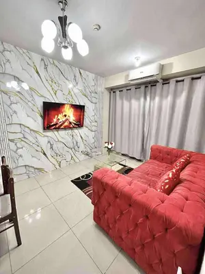 a red couch in a living room with a stone wall at Staycation Near Mall of Asia in Manila