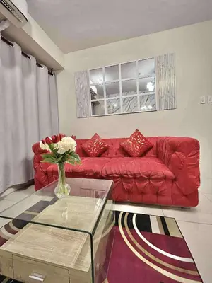 a red couch in a living room with a vase of flowers at Staycation Near Mall of Asia in Manila
