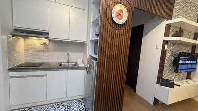 a kitchen with a clock on the wall next to a counter at 1BR Pioneer Woodland Condominium connected to BONI Metro Rail Station,Boni Mandaluyong Metro Manila in Manila
