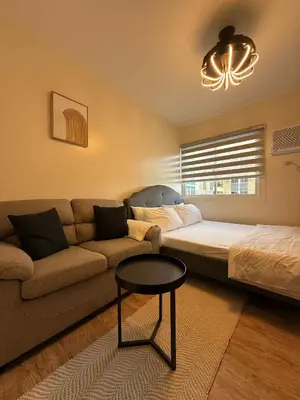a living room with a couch and a bed at Urban Oasis Cozy Studio at Berkeley Suites South Forbes Nuvali in Silang