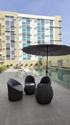 a group of chairs and an umbrella in front of a building at Urban Oasis Cozy Studio at Berkeley Suites South Forbes Nuvali in Silang