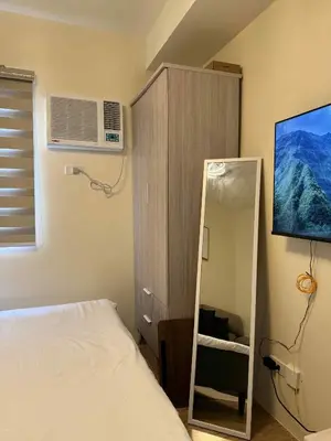 a bedroom with a mirror next to a bed at Urban Oasis Cozy Studio at Berkeley Suites South Forbes Nuvali in Silang