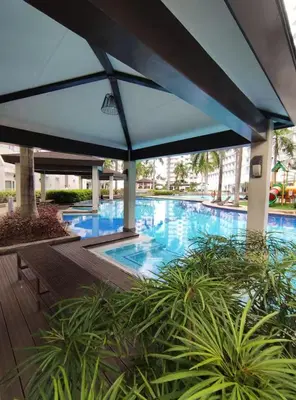 a swimming pool with an umbrella and some plants at Buong tuluyan sa Pasay in Manila