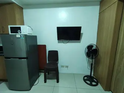 a room with a refrigerator and a chair and a tv at Buong tuluyan sa Pasay in Manila