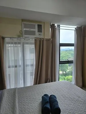 a pair of blue jeans sitting on a bed with a window at Condo unit in Taguig in Manila