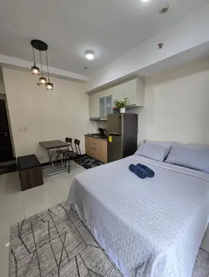 a bedroom with a large white bed and a kitchen at Condo unit in Taguig in Manila