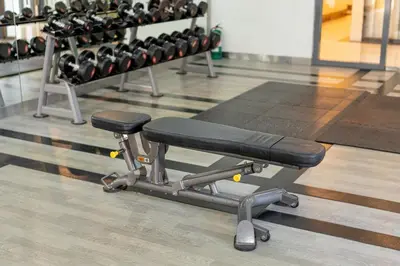 a gym with a bench and lots of weights at Stingga McKinley Aesthetic Studio in Venice in Manila