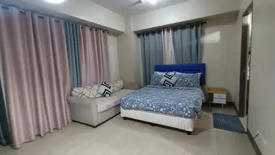 a bedroom with a bed and a couch and curtains at Asthrea Condotels in front of NAIA Terminal 3 Airport in Manila