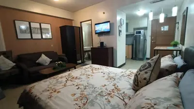 a room with a bed and a couch and a tv at Asthrea Condotels in front of NAIA Terminal 3 Airport in Manila