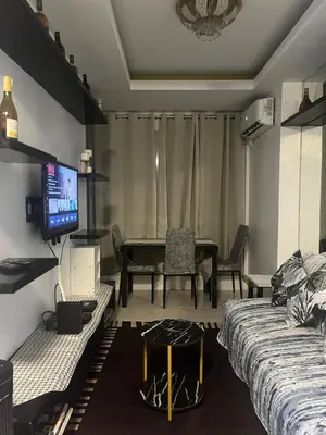 a living room with a table and a tv in it at JFS Home at Birch Tower 1BR in Manila