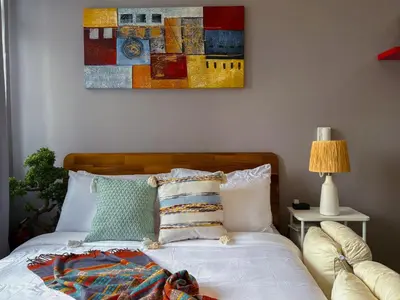 a bedroom with a bed with a painting on the wall at Hidden Village at Gramercy Residences - APARTMENT with Infinity Pool Sauna Gym in Manila