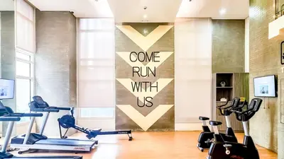 a gym with cardio equipment and a wall with a sign at Central Makati Studio with Gym Pool and Massage Room in Manila