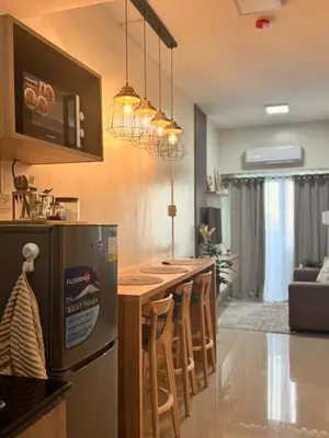 a kitchen with a bar with chairs and a refrigerator at Cozy 1-Bedroom Staycation near NAIA & Mall of Asia in Manila