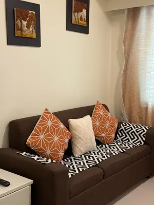 a brown couch with pillows on it in a living room at Sea Residences Staycation SMDC Property in Manila