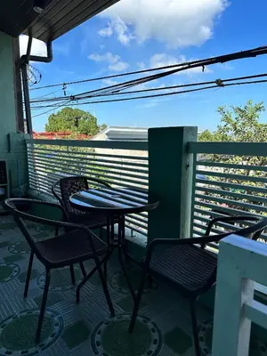a patio with tables and chairs on a balcony at SJ Vistacation in Tanza