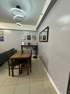 a dining room with a table and chairs and a lamp at Ezras Place Modern Condo with City views in Manila