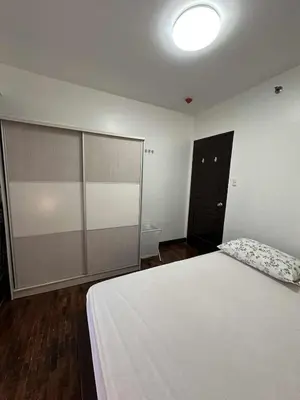 a bedroom with a white bed and a black door at Cypress Towers Staycation in Manila