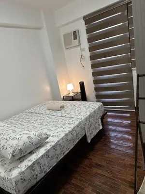 a bedroom with a bed with a white comforter at Cypress Towers Staycation in Manila