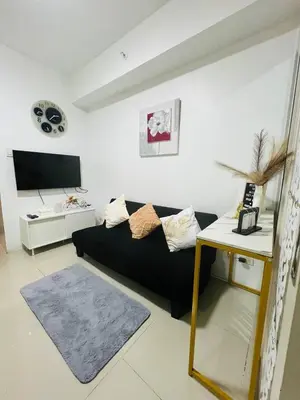 a living room with a black couch and a table at Allie's Cozy Place at Sea Residences in Manila