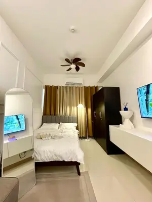 a bedroom with a bed and a ceiling fan at Lush Urban Studio in Manila