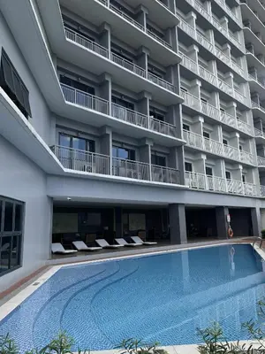 a hotel with a swimming pool in front of a building at Lush Urban Studio in Manila