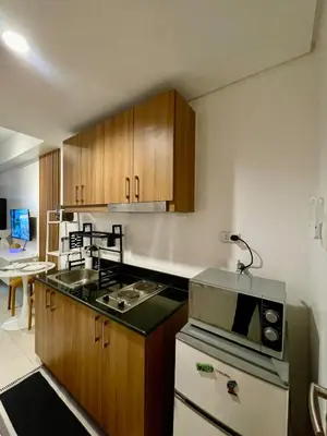 a kitchen with wooden cabinets and a stove top oven at Lush Urban Studio in Manila