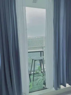 a window with a chair sitting on a balcony at Azure staycation By Icay in Manila