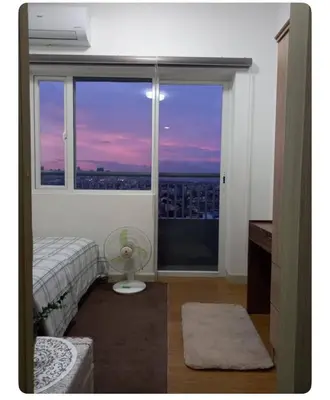 a bedroom with a window with a view of a city at John's place near BGC and Airport in Manila