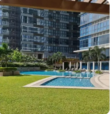 a swimming pool in front of a large building at Mysuites2go24K Parksuites T2 in Manila