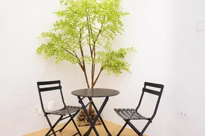 two chairs and a table with a tree in a room at Ephram House - A-Frame Cabin Staycation with Pool, Games & BBQ For Up To 20 Guests in Bacoor